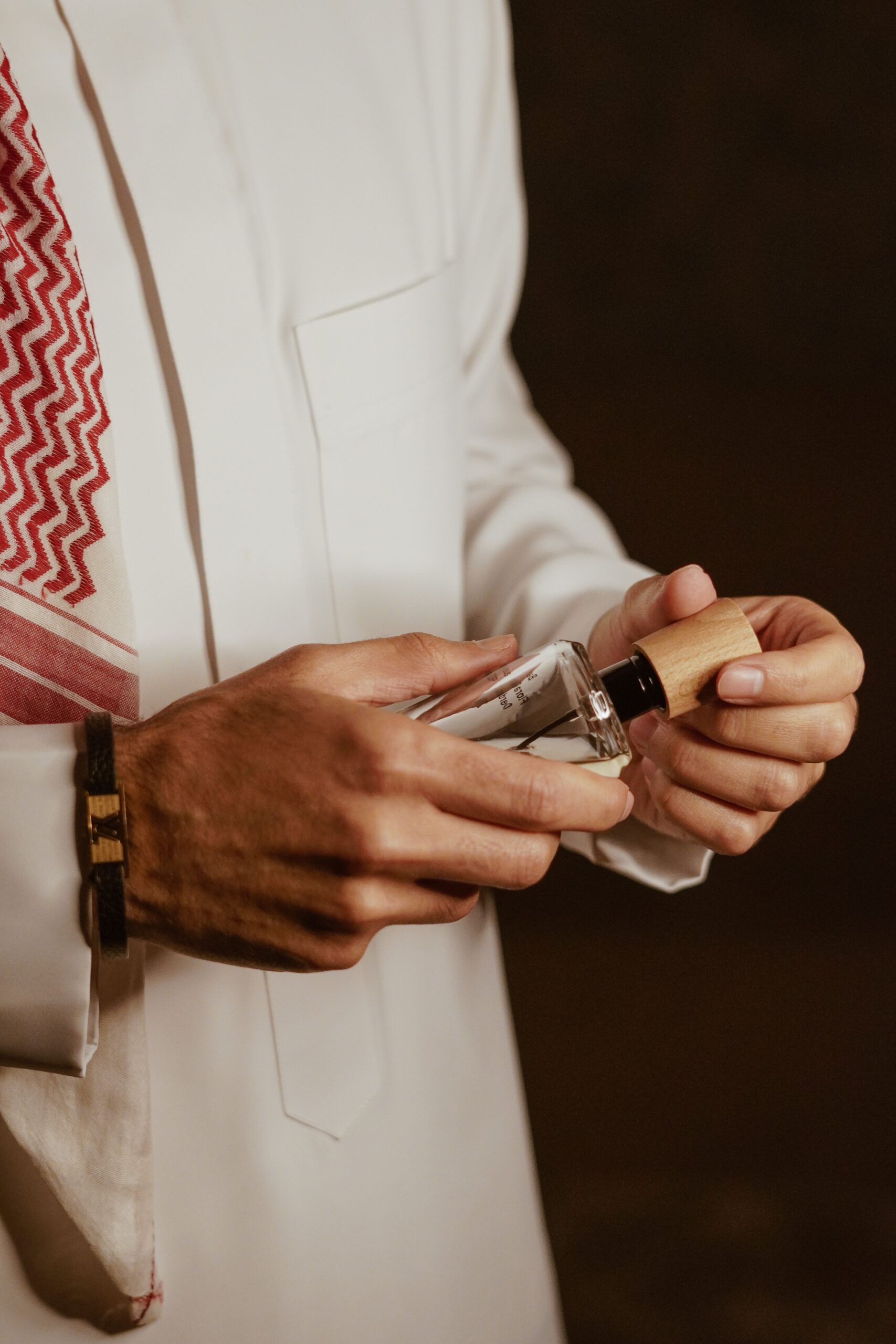 Close-up of a man's hands holding a perfume bottle with elegance and style.